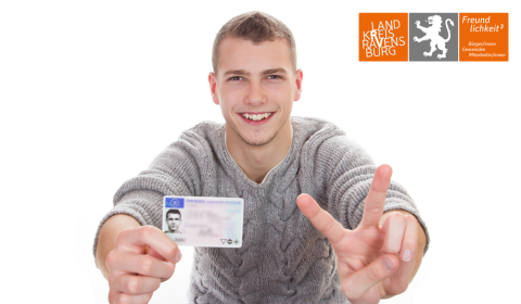 Führerscheinpflichtumtausch junger lächelnder weißhäutiger Mann hält einen Kartenführerschein ins Bild, in der rechten oberen Ecke das Landkreislogo.