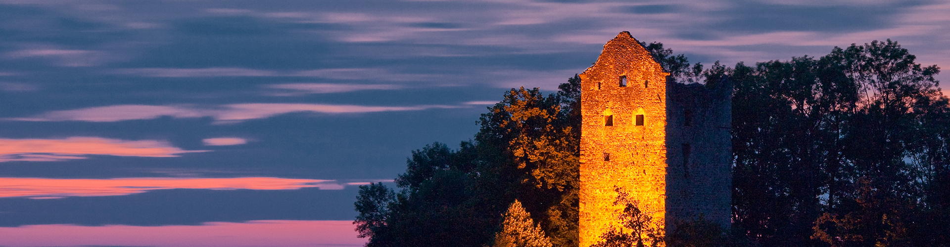 Burgruinenturm bei Sonnenuntergangsstimmung und leicht bewölktem Himmel